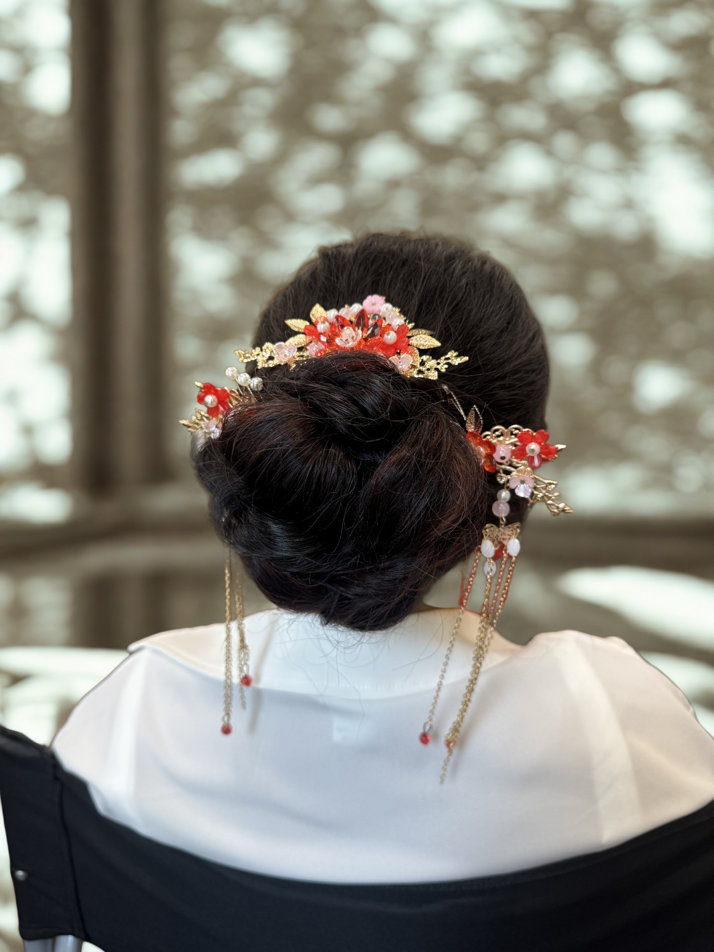 Sleek low bun with a red and gold floral hairpiece