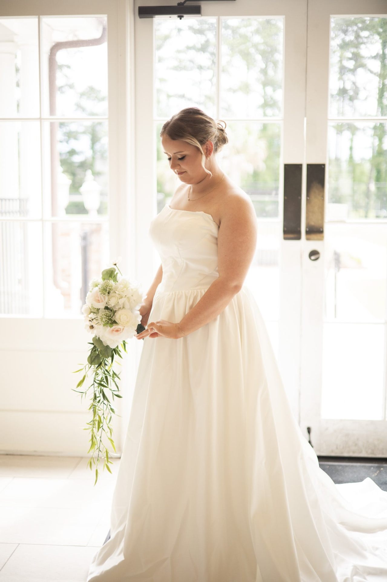Real bride with soft updo and natural glam in a sunlit doorway